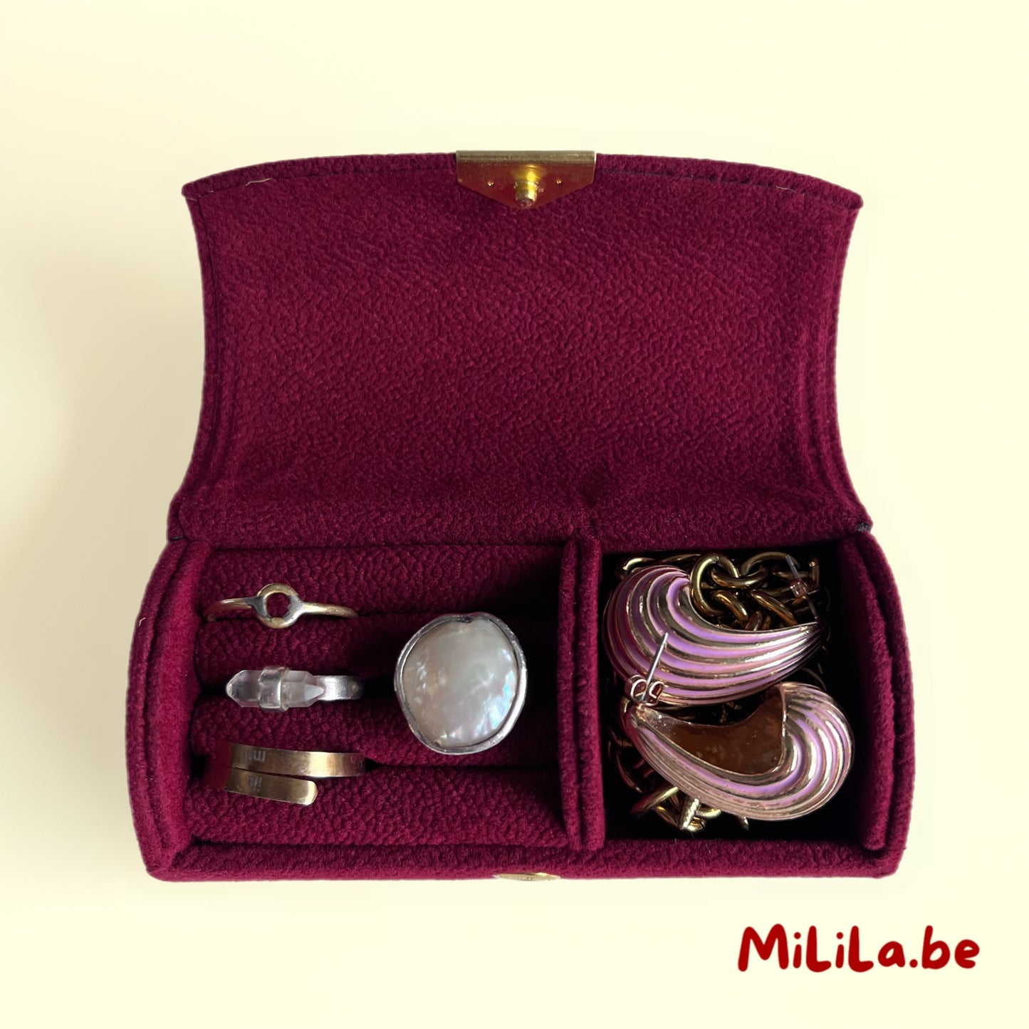 Open compact bordeaux juwelendoosje met ringen, oorbellen en ketting